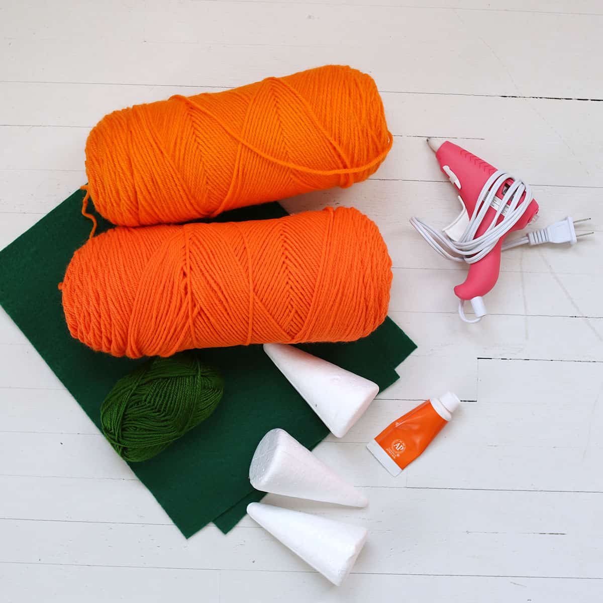 orange yarn, green felt, styrofoam cones, and glue gun.