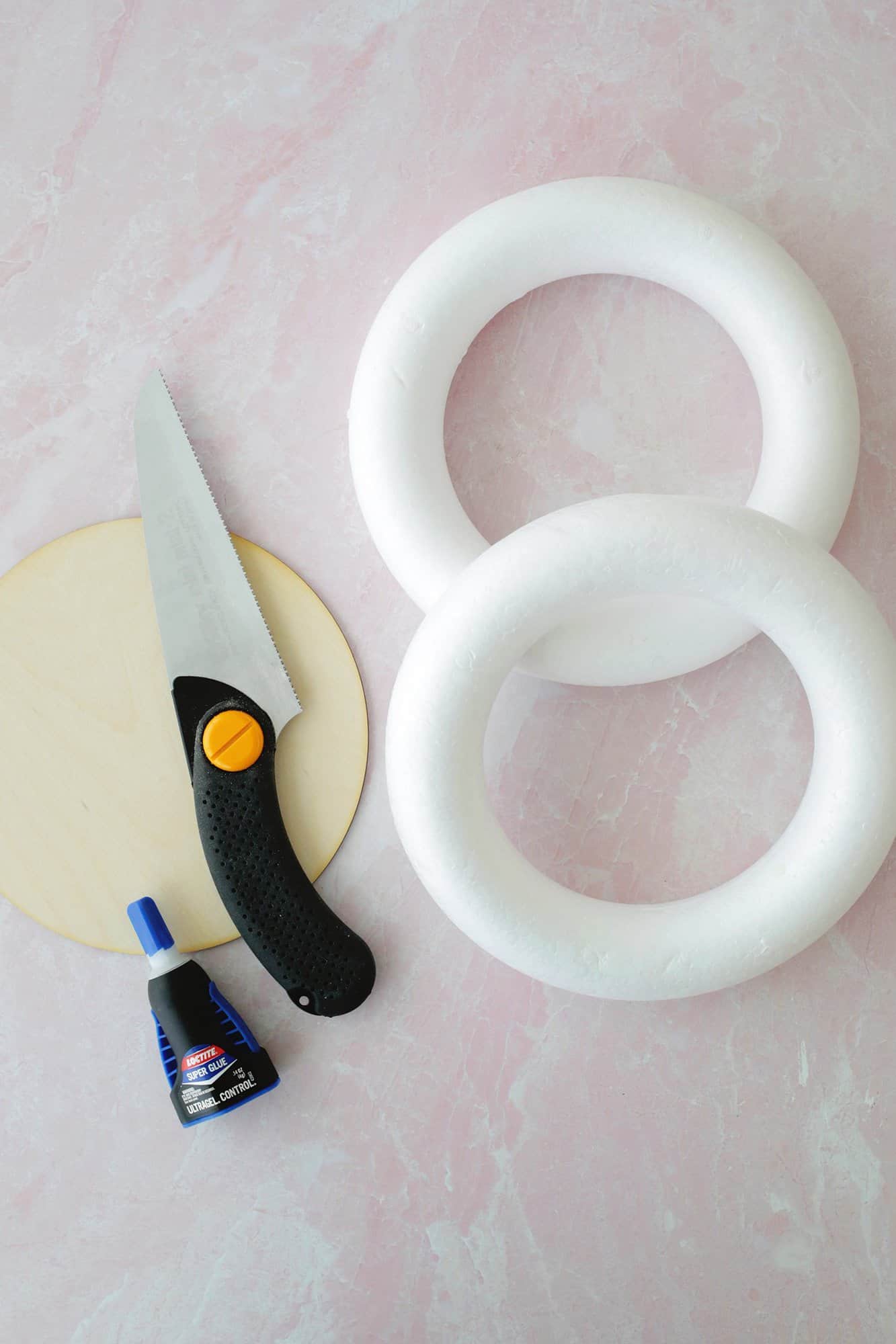 Foam wreath rings, a wooden circle and glue, and a handsaw