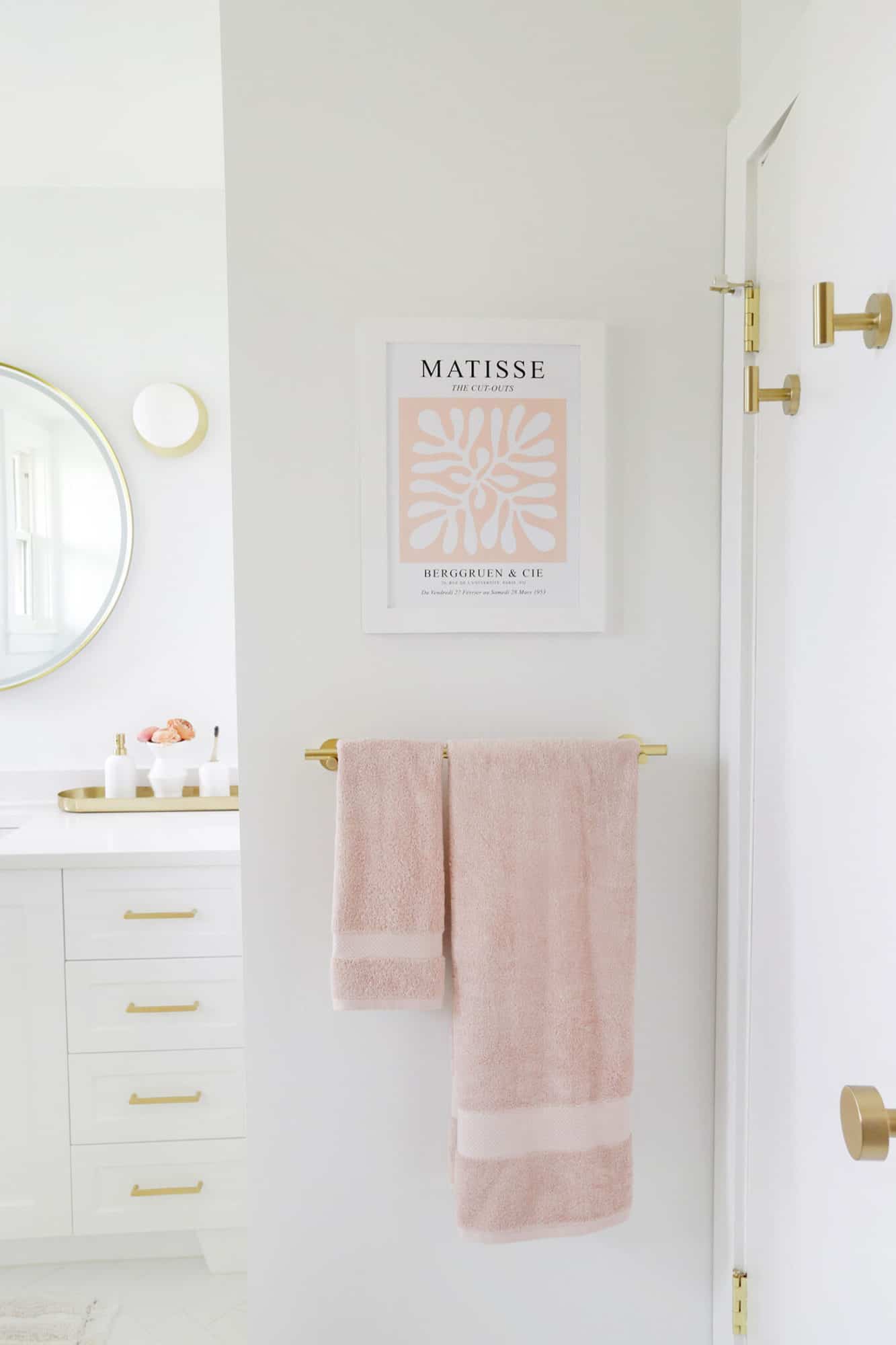 towel rack with pink towels and matisse print above it