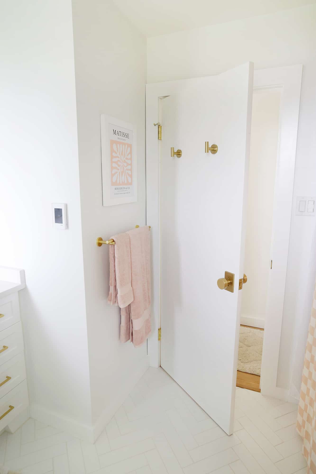 towel rack with pink towels and matisse print above it
