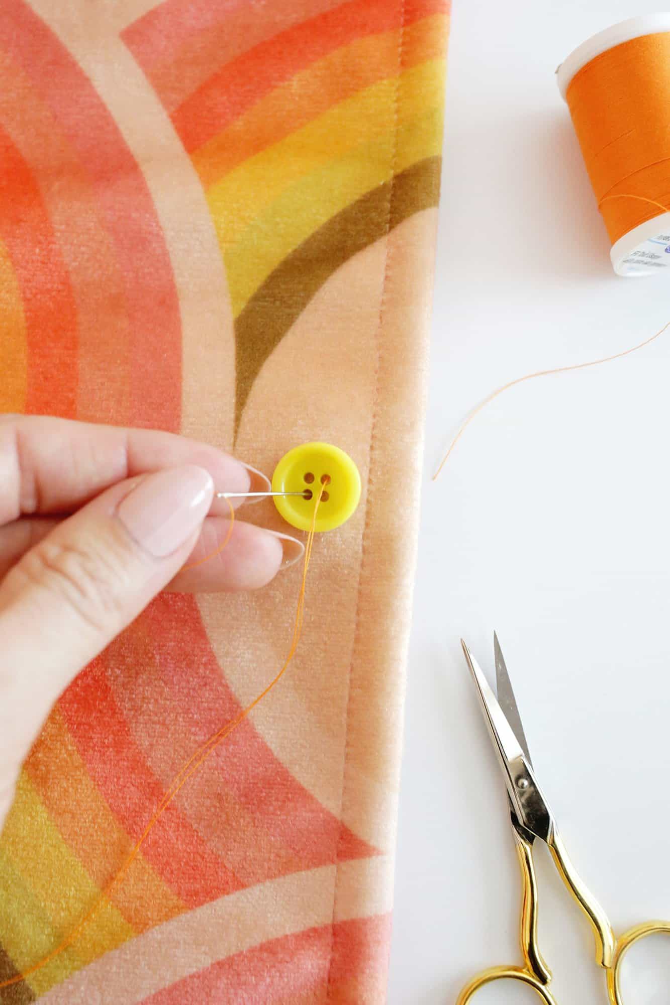 needle passing through a buttonhole to sew a button