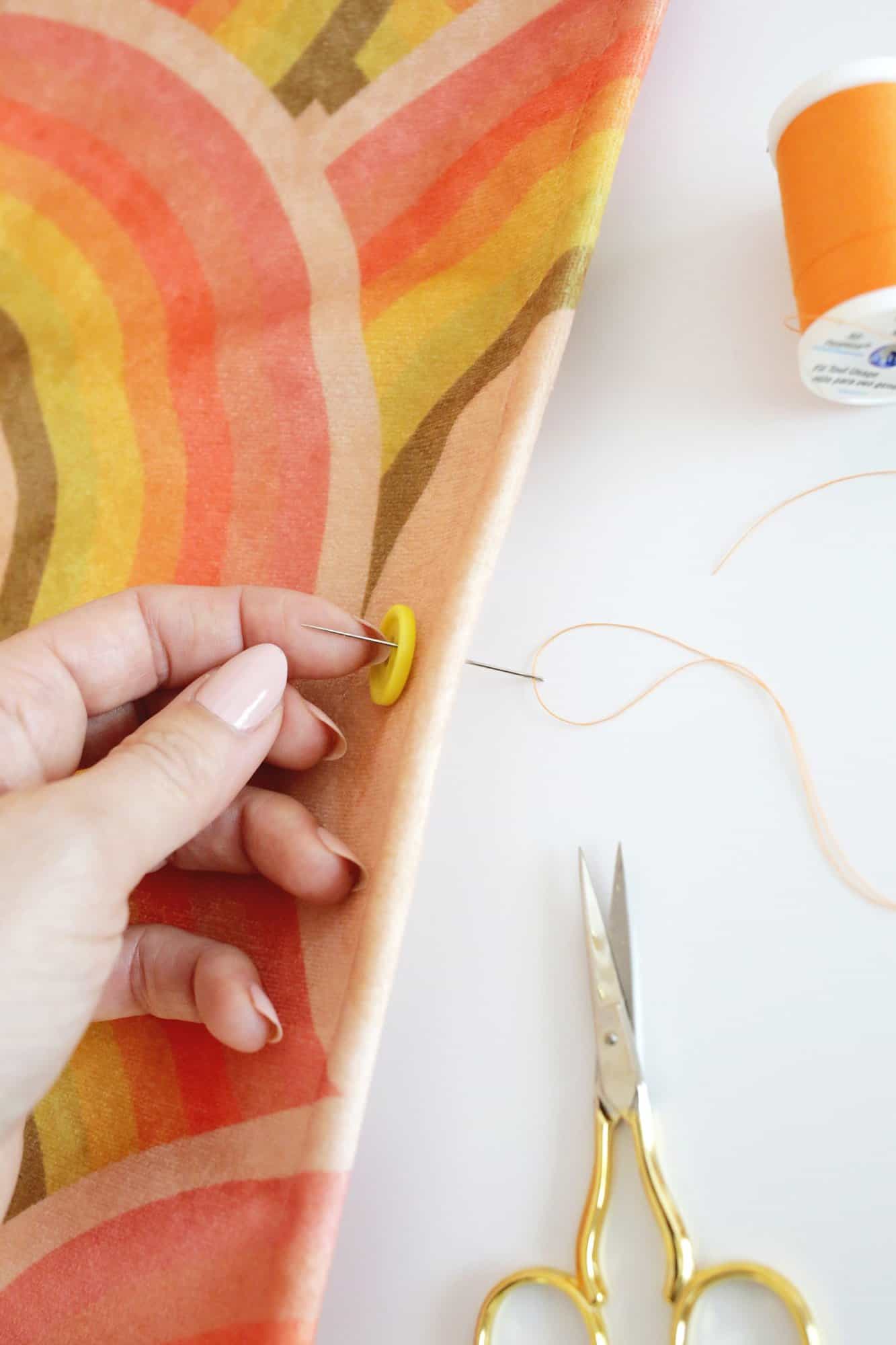 needle passing through fabric to sew a button