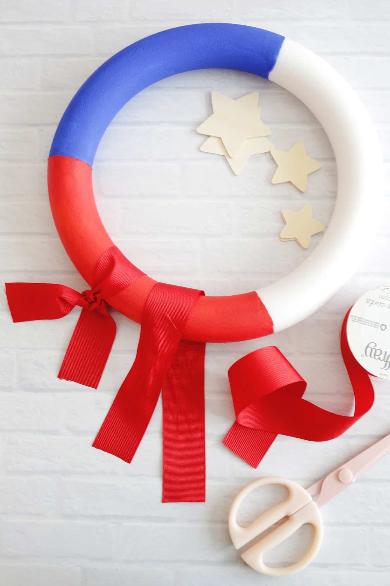 tying red ribbons around wreath
