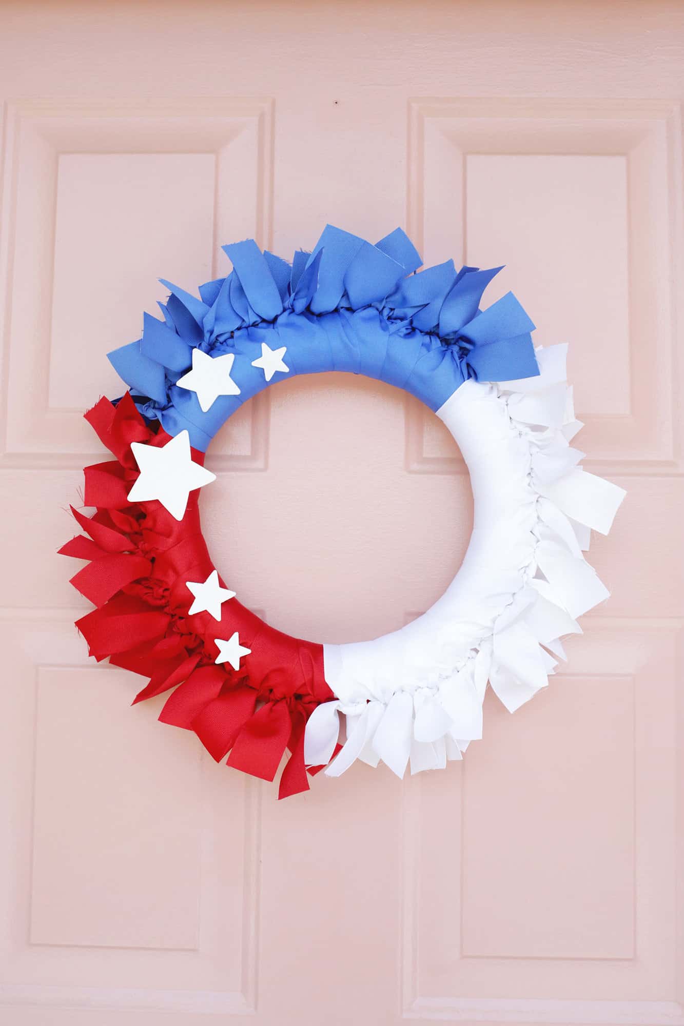 red, white and blue ribbon wreath on pink door