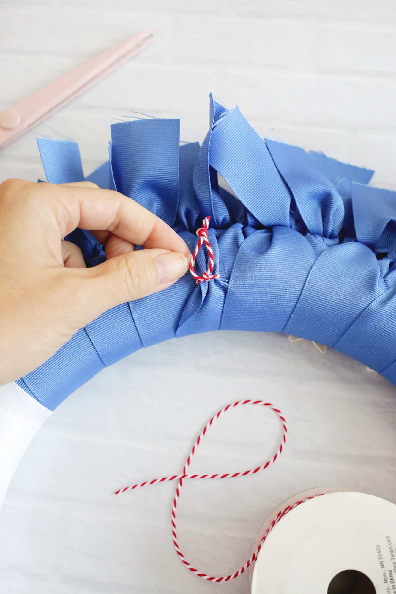 twine loop being tied to the back of a ribbon wreath