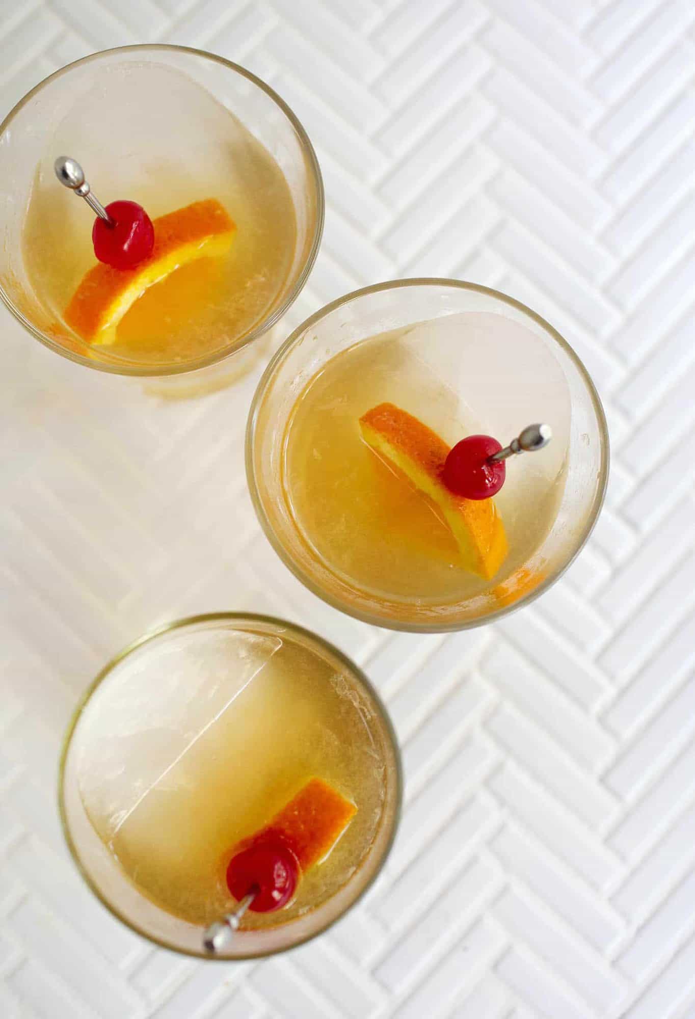 amaretto sour cocktail in glass with cherry and orange garnish. 