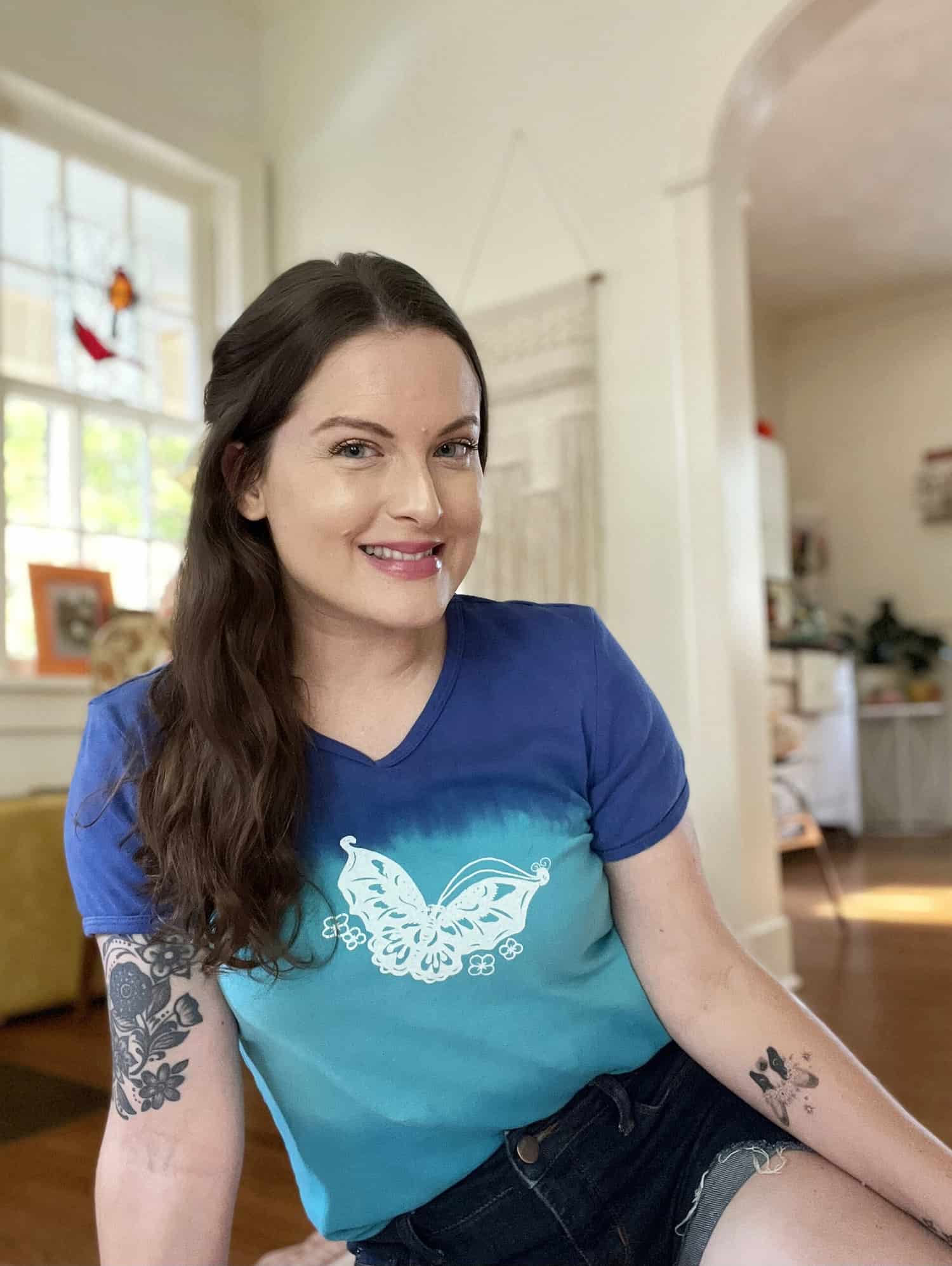 Girl posing in living room wearing a blue butterfly shirt 