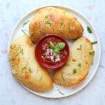 three calzones on a plate with red sauce