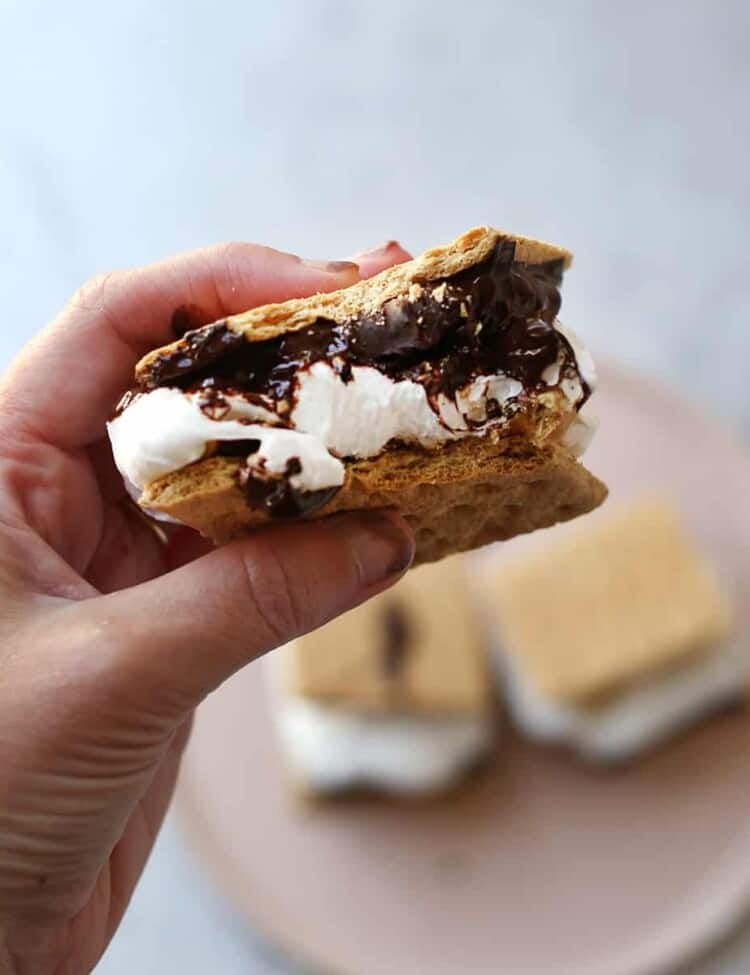 hand holding a s'more sandwich with a bite taken out
