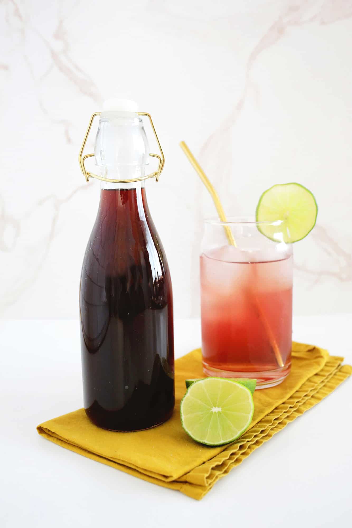 Bottle of homemade grenadine next to a cocktail