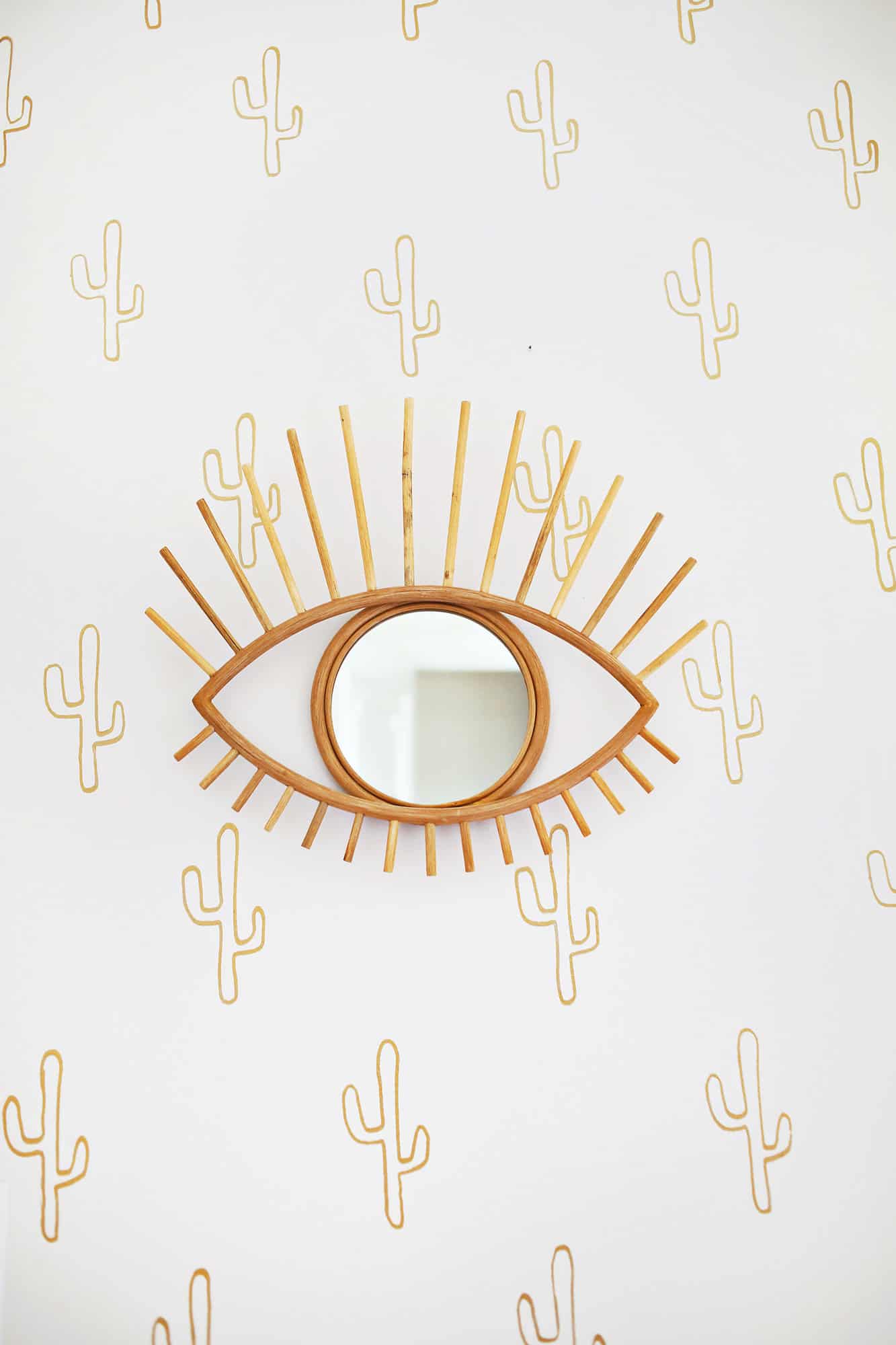 eye mirror on wall with cactus wallpaper