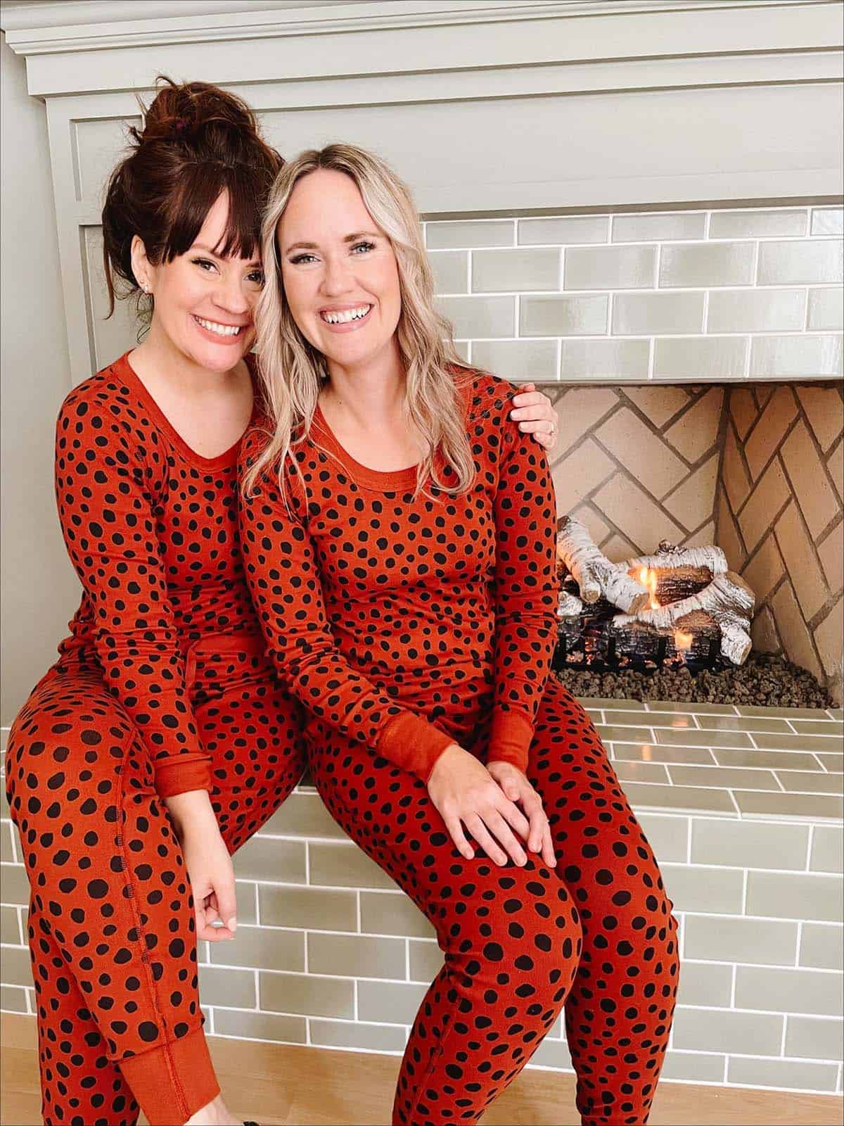 two women in pajamas by the fireplace