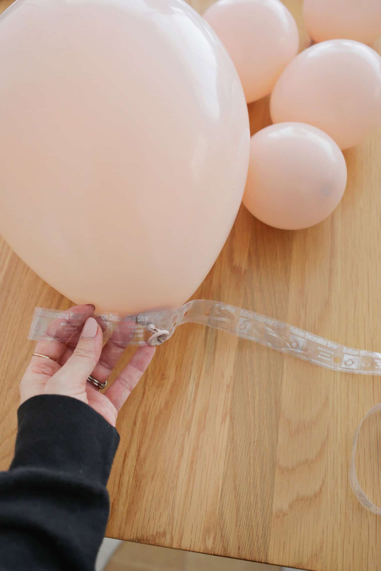 adding pink balloons to balloon garland strip