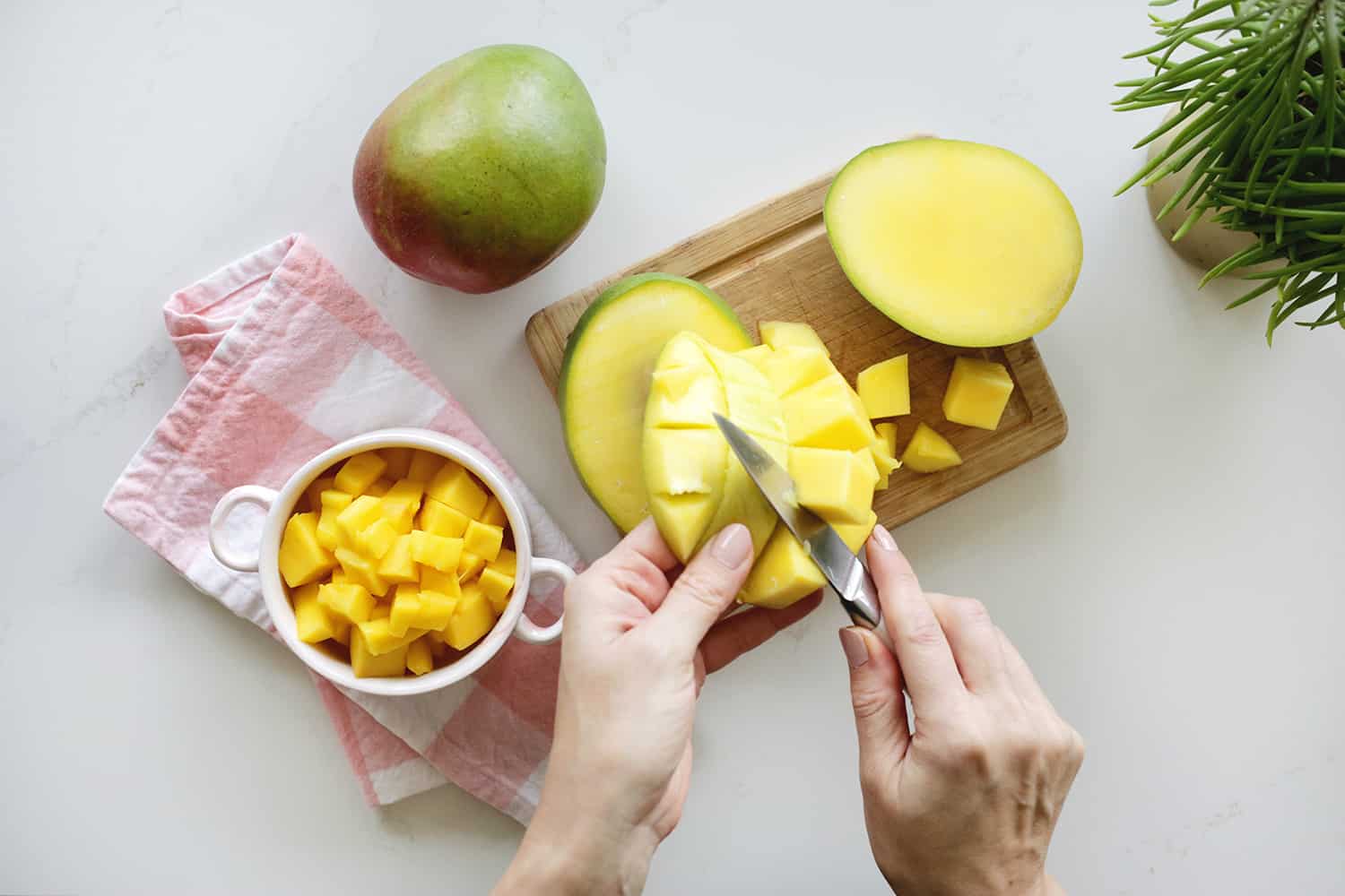 Hand cutting out cubed mango chunks