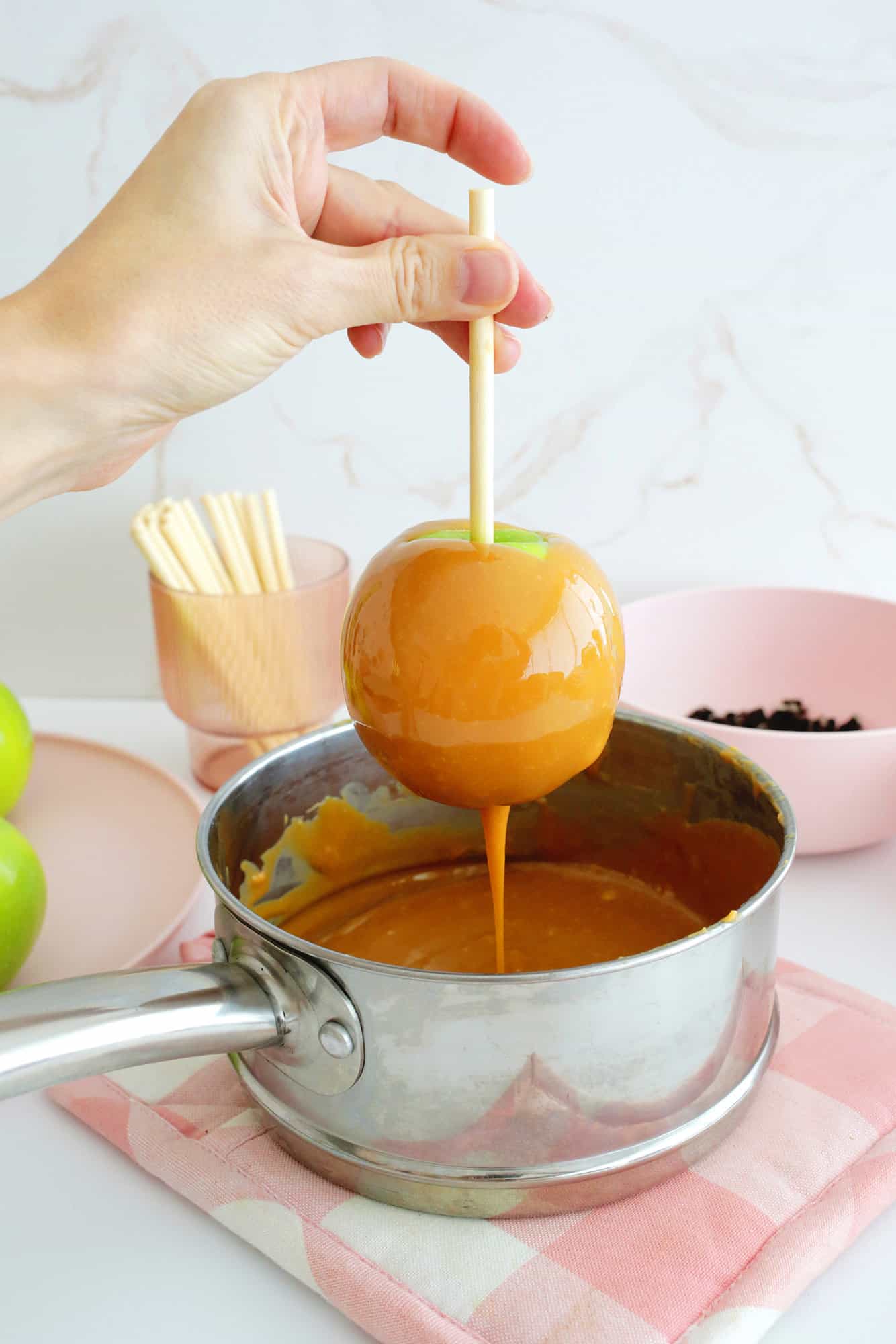 Dipping an apple into caramel for caramel apples