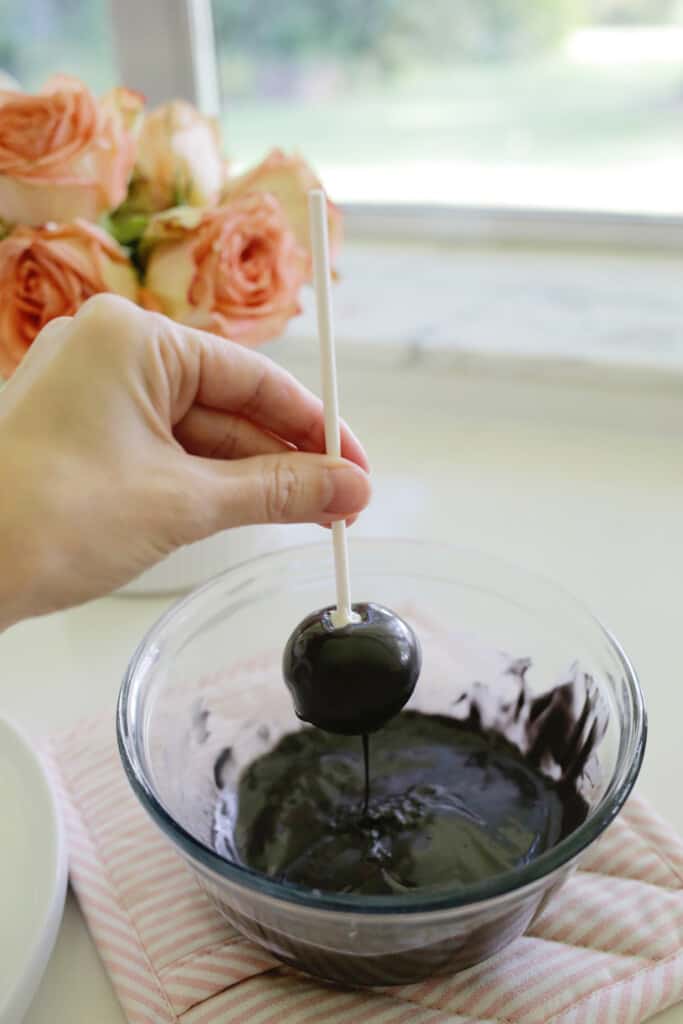 dipping cake pop into melted chocolate