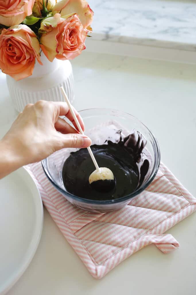dipping cake pop into melted chocolate