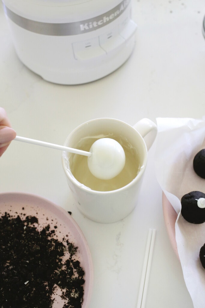 Dipping oreo cake pop balls into melted chocolate