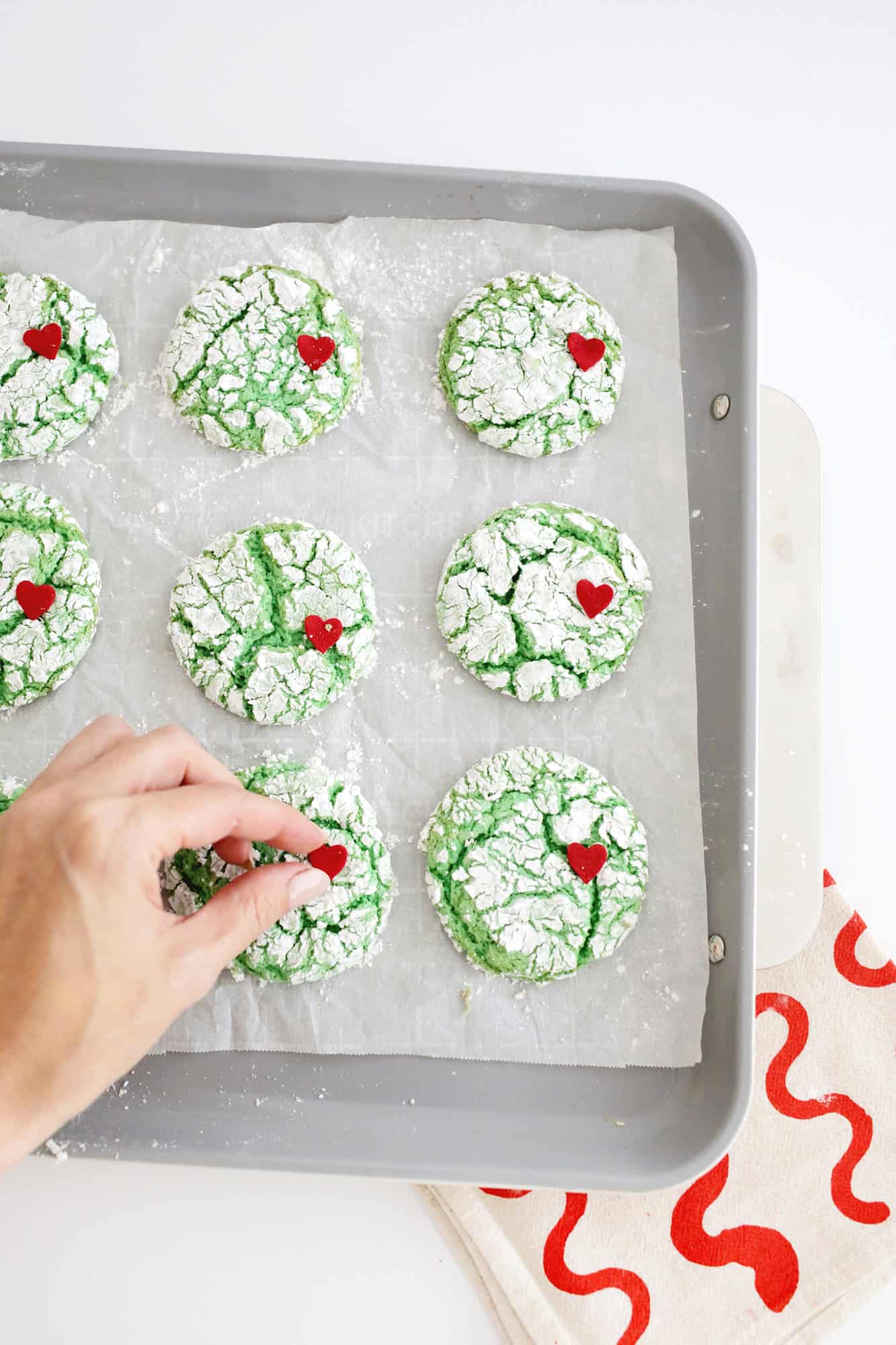 adding heart sprinkles to grinch cookie