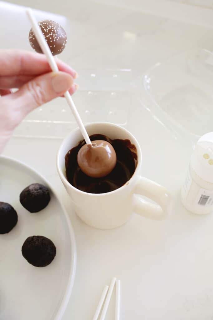 dipping chocolate cake pop into melted chocolate