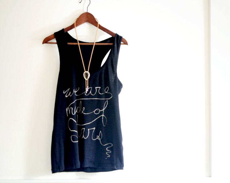 a blue tank top hanging on a hanger with bleached writing on it