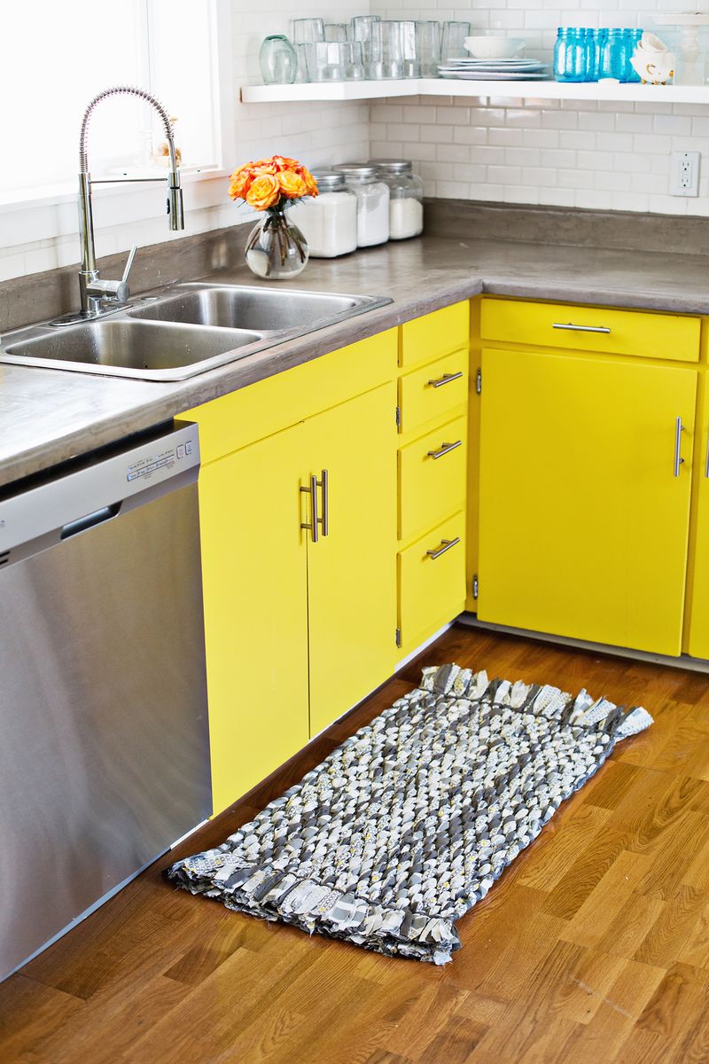 kitchen with yellow cabinets and a woven rag rug on the floor