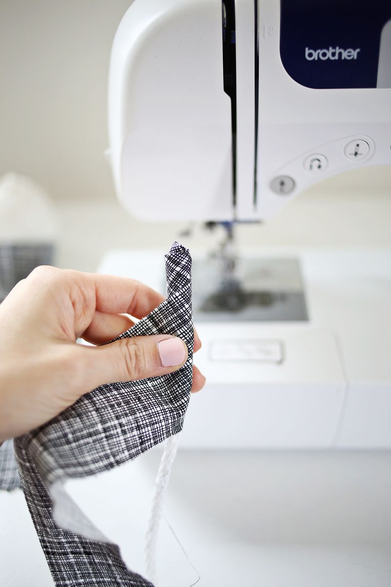 someone holding up a black and white strip of fabric in front of a sewing machine