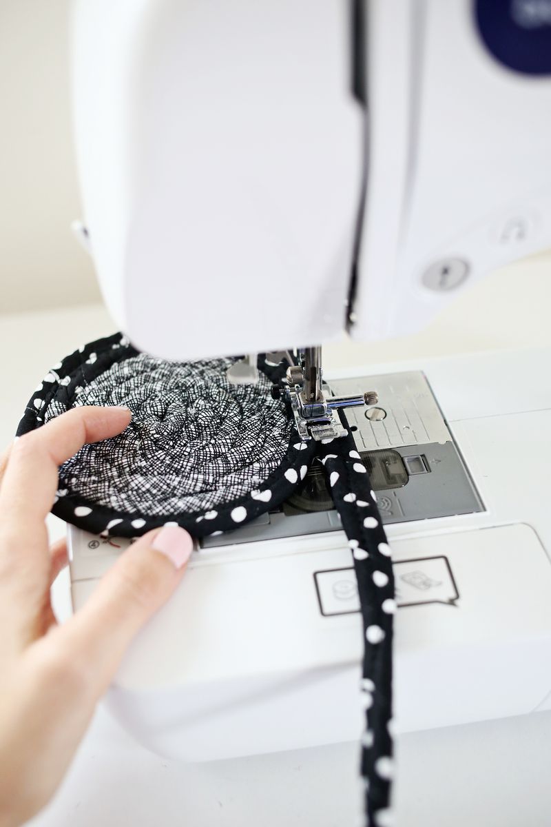 a black with white polka dots strip of fabric being sewn to a black and white strip of fabric in a sewing machine