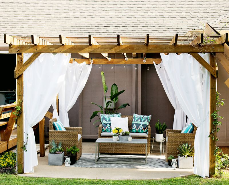 4 outdoor curtains on a wooden deck cover with wicker patio furniture underneath it