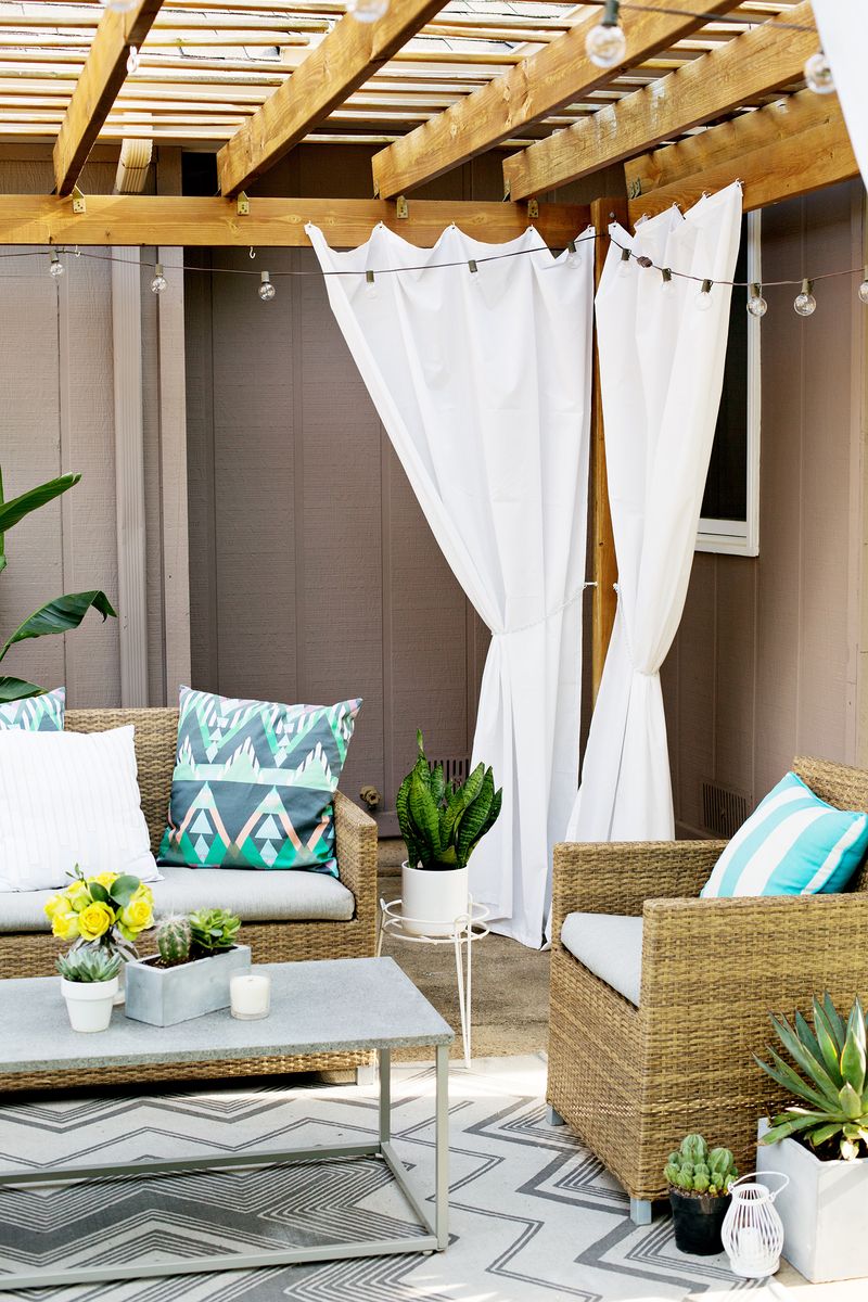 corner of wooden deck cover with outdoor curtains and wicker patio furniture