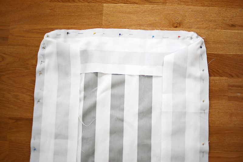 gray and white stripped fabric being pinned to white fabric