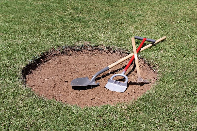 dug up circle shaped hole with shovel, mattock, and other digging tool