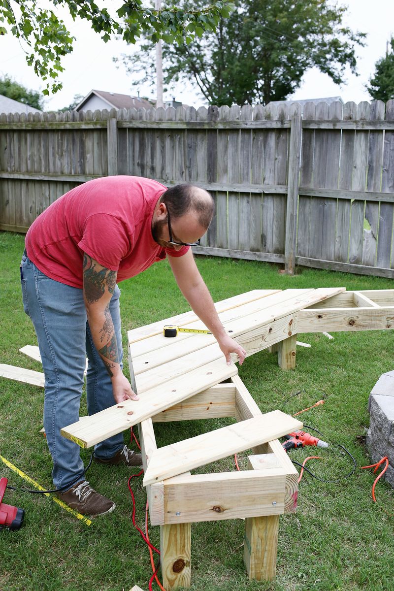 a man building the seat slats for the fire pit bench
