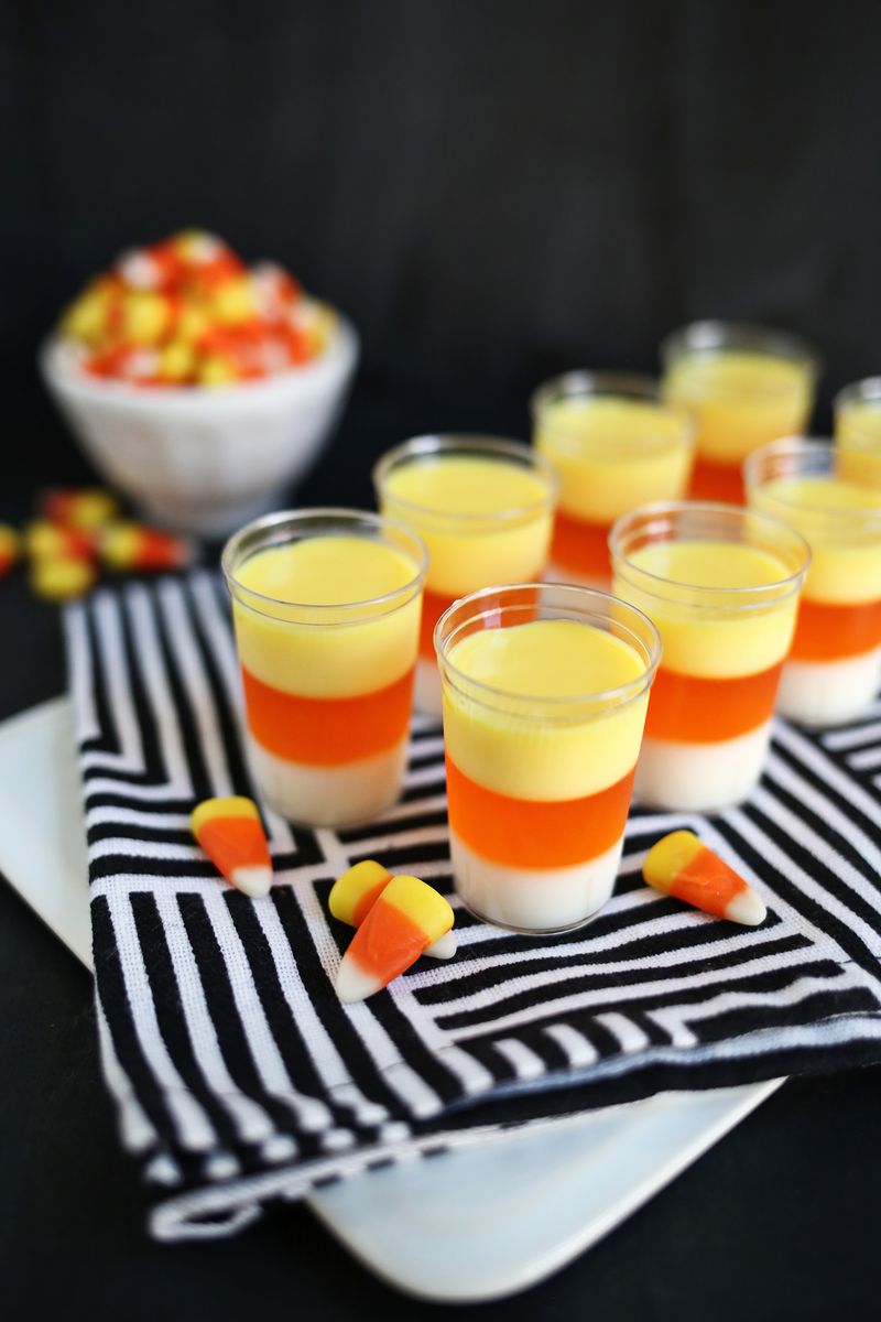 8 candy corn jello shots with a bowl of candy corn by them