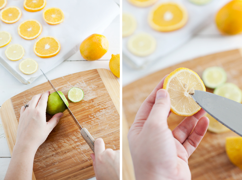 someone cutting lemons and limes on a cutting board