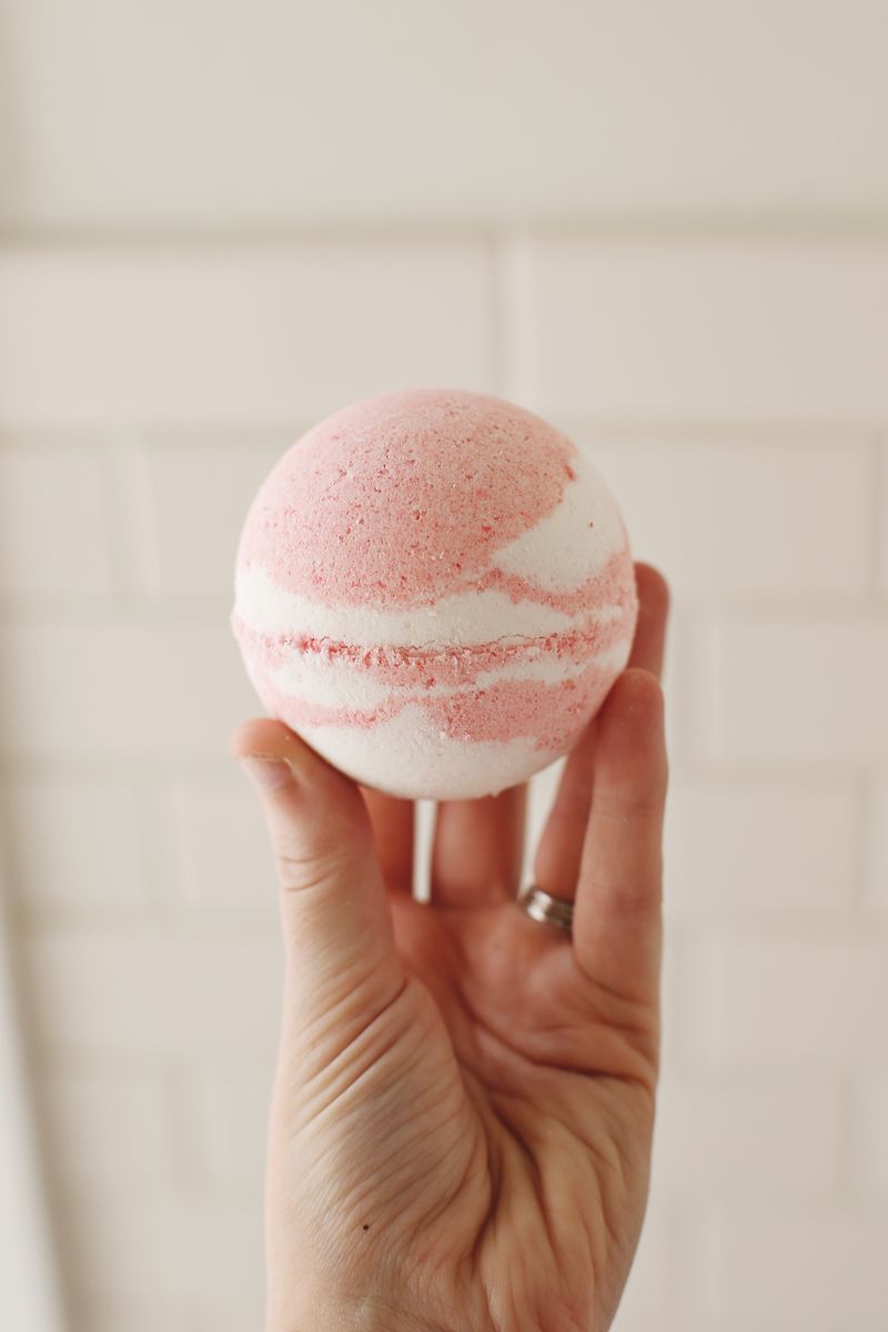 somone holding up a pink and white homemade bath bomb