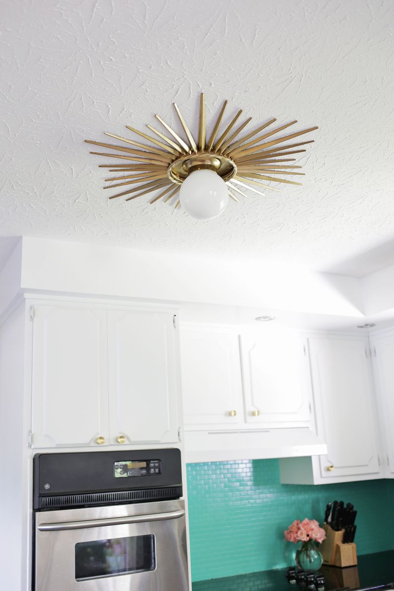 sunburst mirror medalion around light fixture in a white kitchen