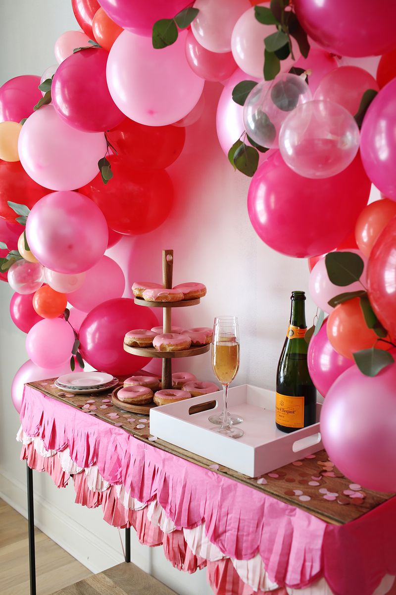 a balloon arch over a table with cookies and drinks on it