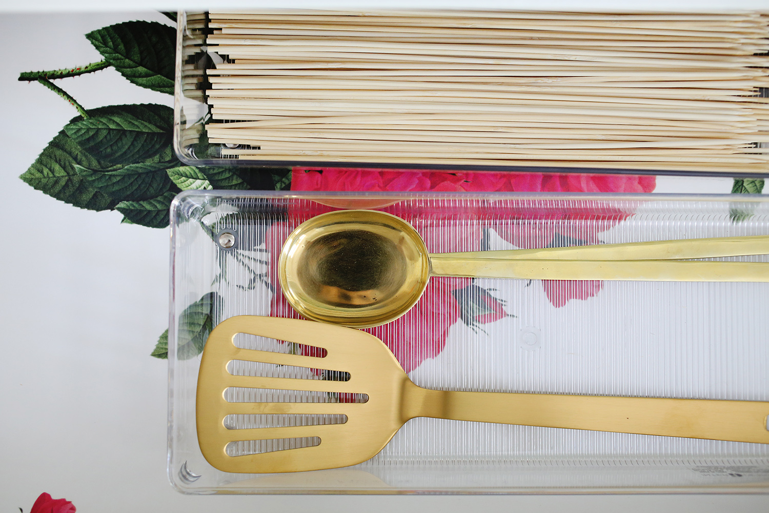 gold spatula and spoon in a clear container and wooden sticks in a clear container