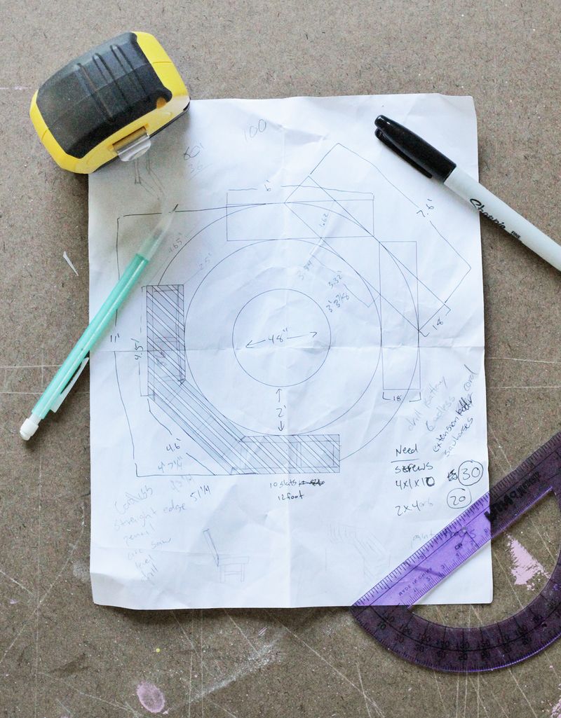 paper with plans for firepit drawn on it, a pencil, a sharpie, a ruler, and a tape measurer