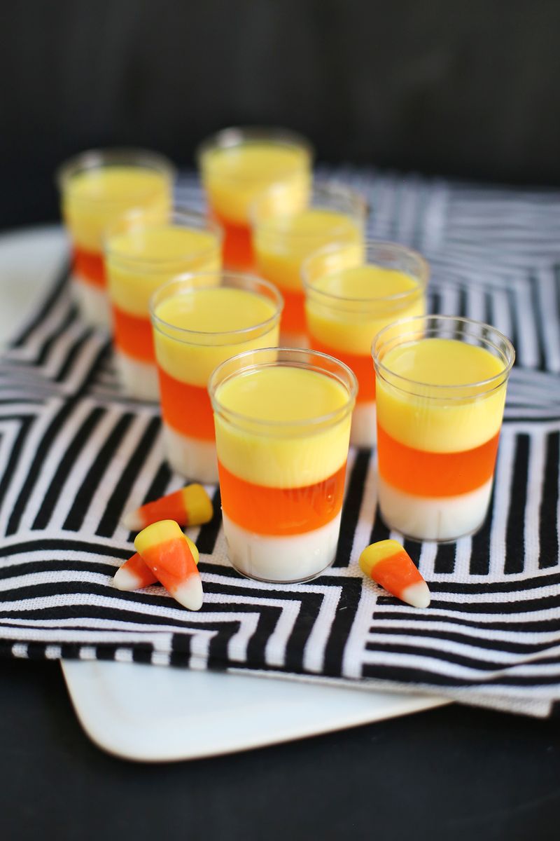 8 candy corn jello shots on a black and white towel with candy corn on it