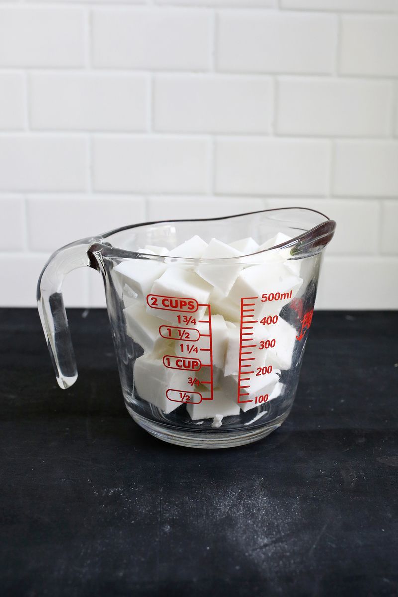 a glass measuring cup with white cubes of melt and pour soap