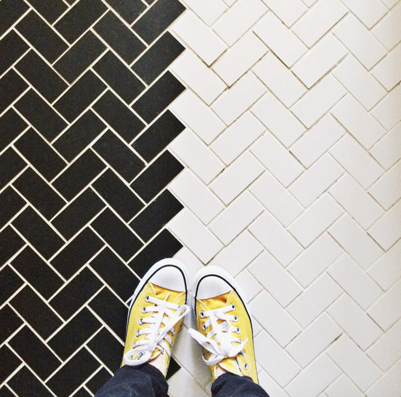 Black and white herringbone tile with yellow sneakers on it