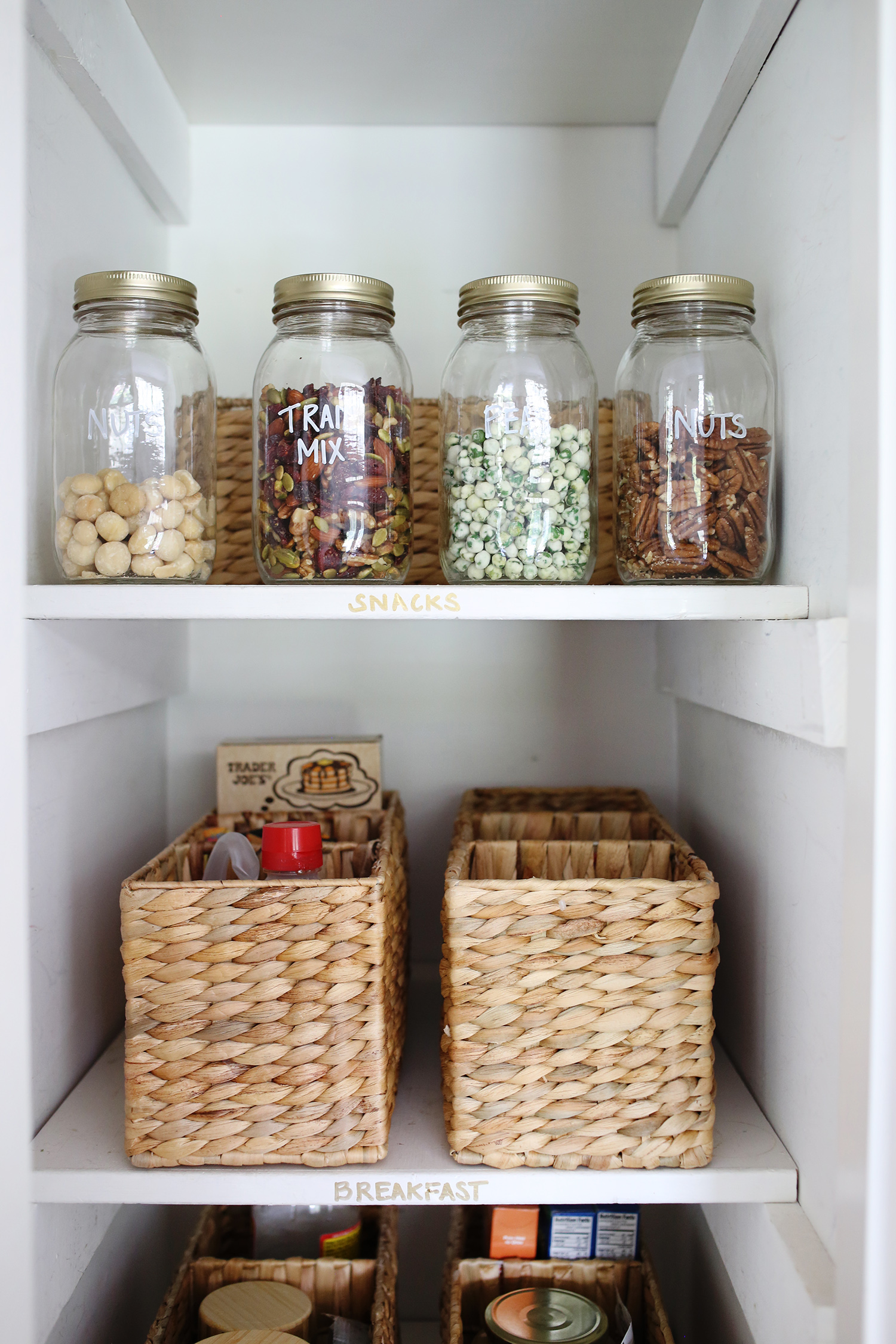 view of inside the pantry with jars of nuts and baskets on shelves