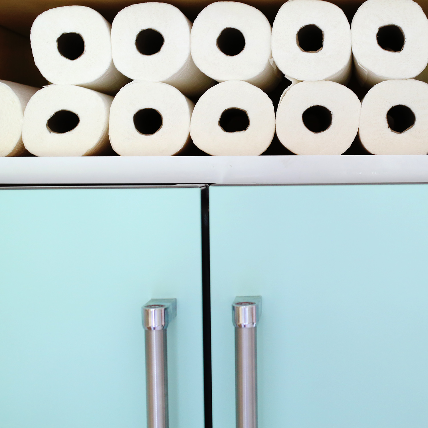 teal cabinets with rolls of paper towels on top