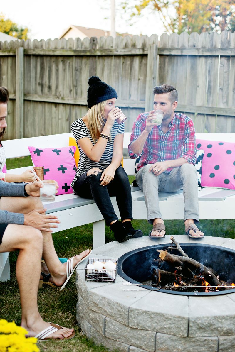 a couple looking at each other while drinking with feet propped on fire pit