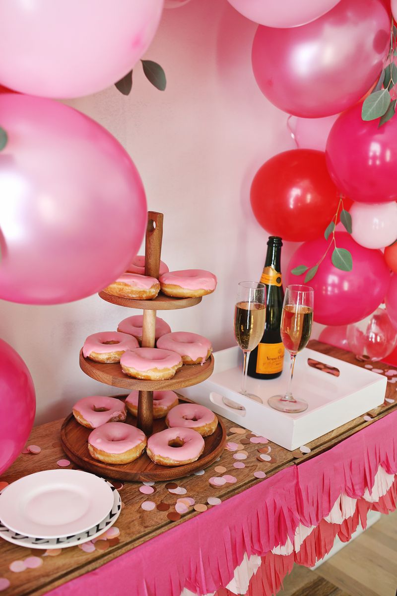 a close up of the cookies and drinks on the table with the balloon arch over it