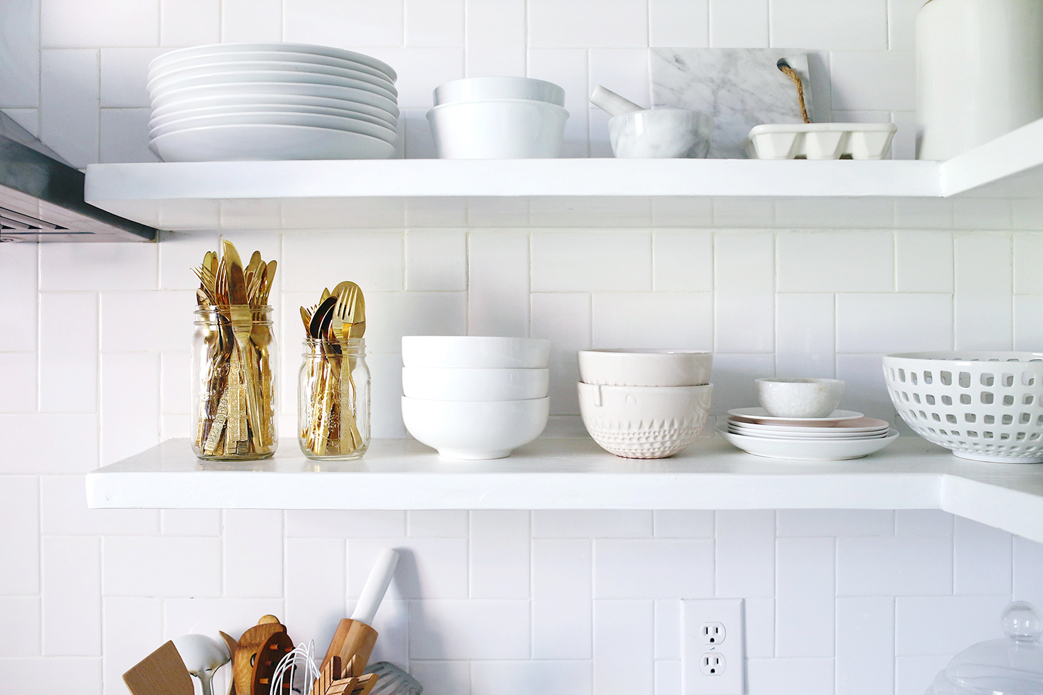 whiteshelves with white dishes on it and gold silverware in jars