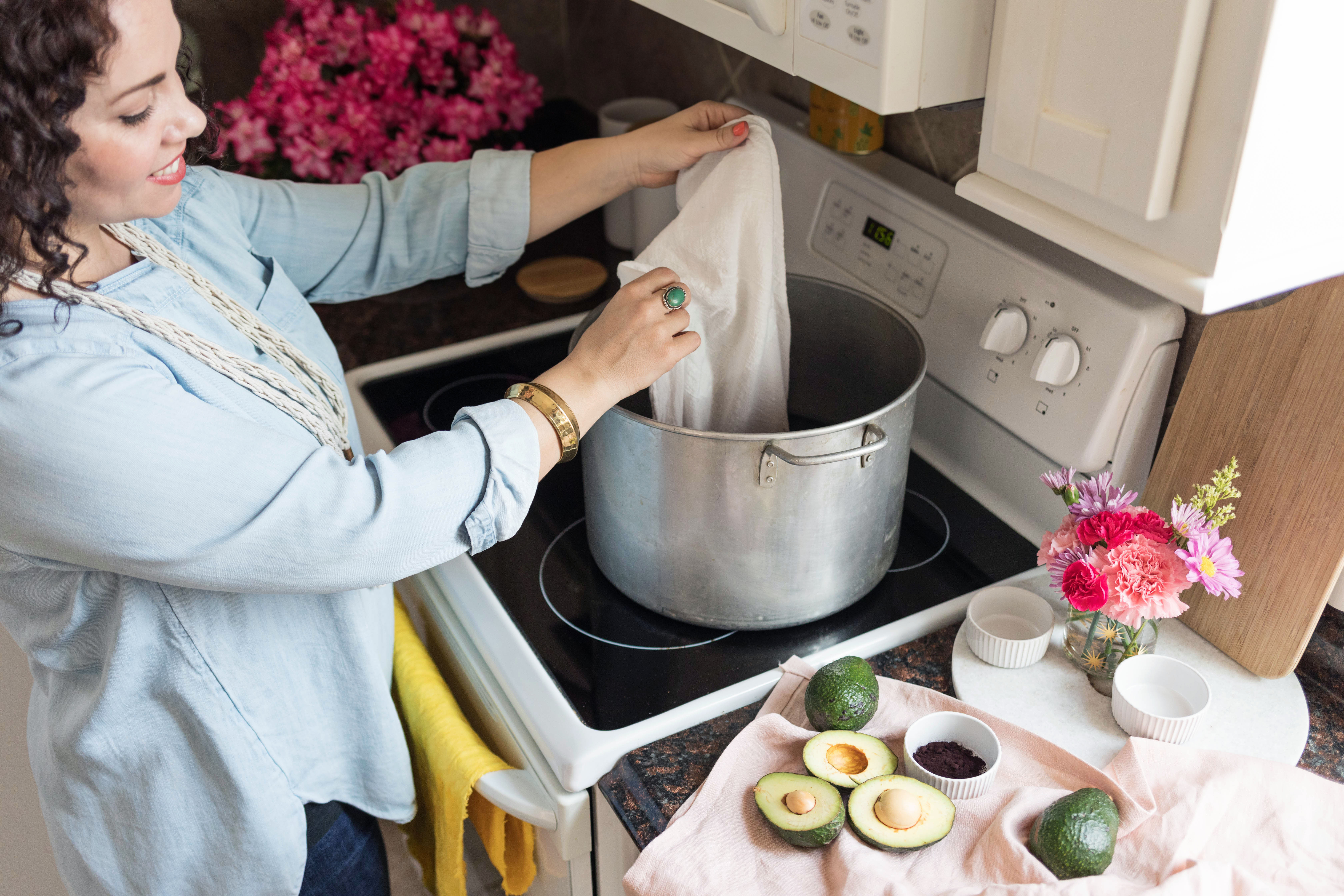 a woman put a white canvas bag in a big metal pot on a stove